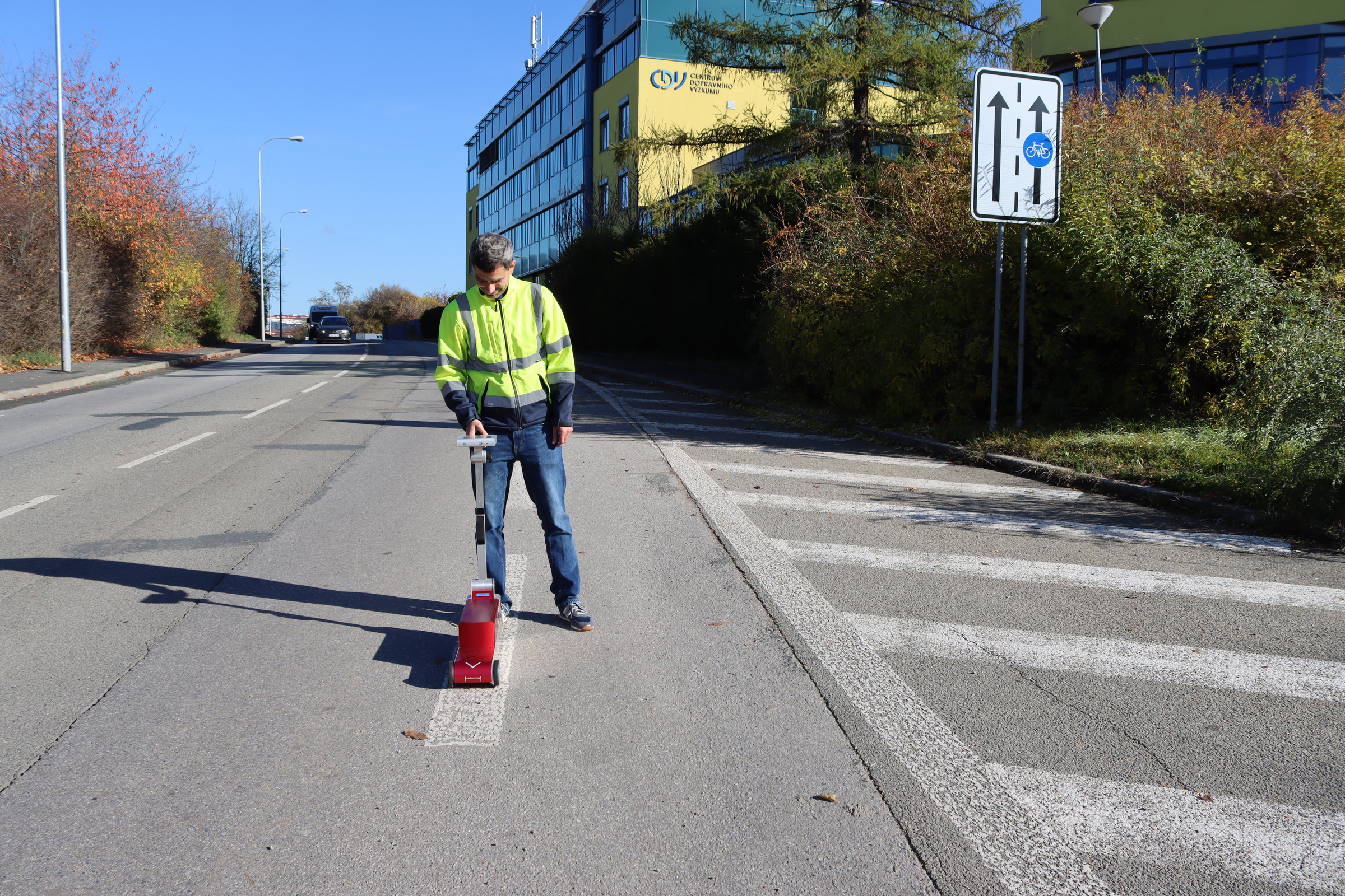 Muž měří kvalitu vodorovného dopravního značení