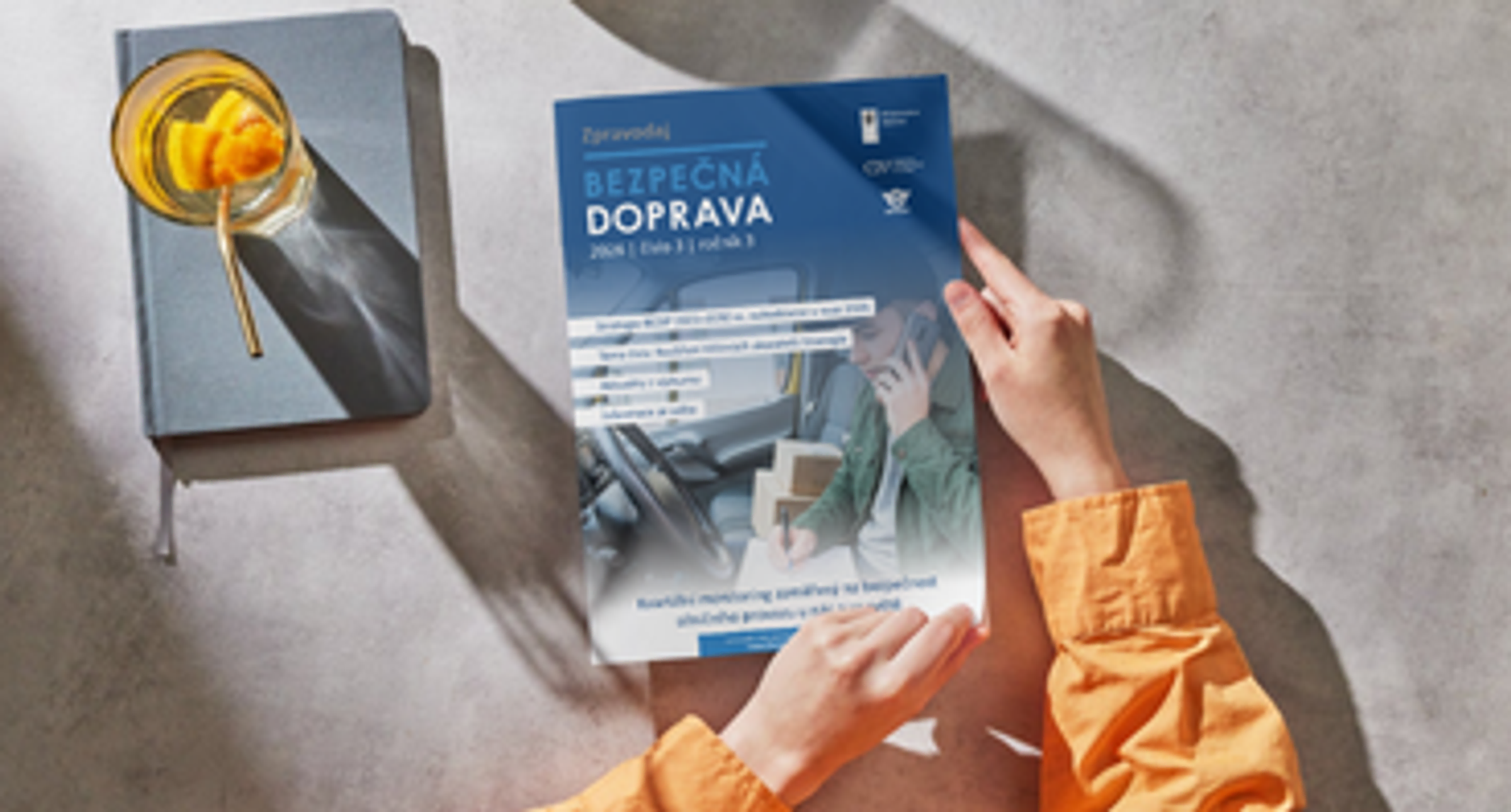 žena sedí u stolu s vydáním zpravodaje Bezpečná doprava