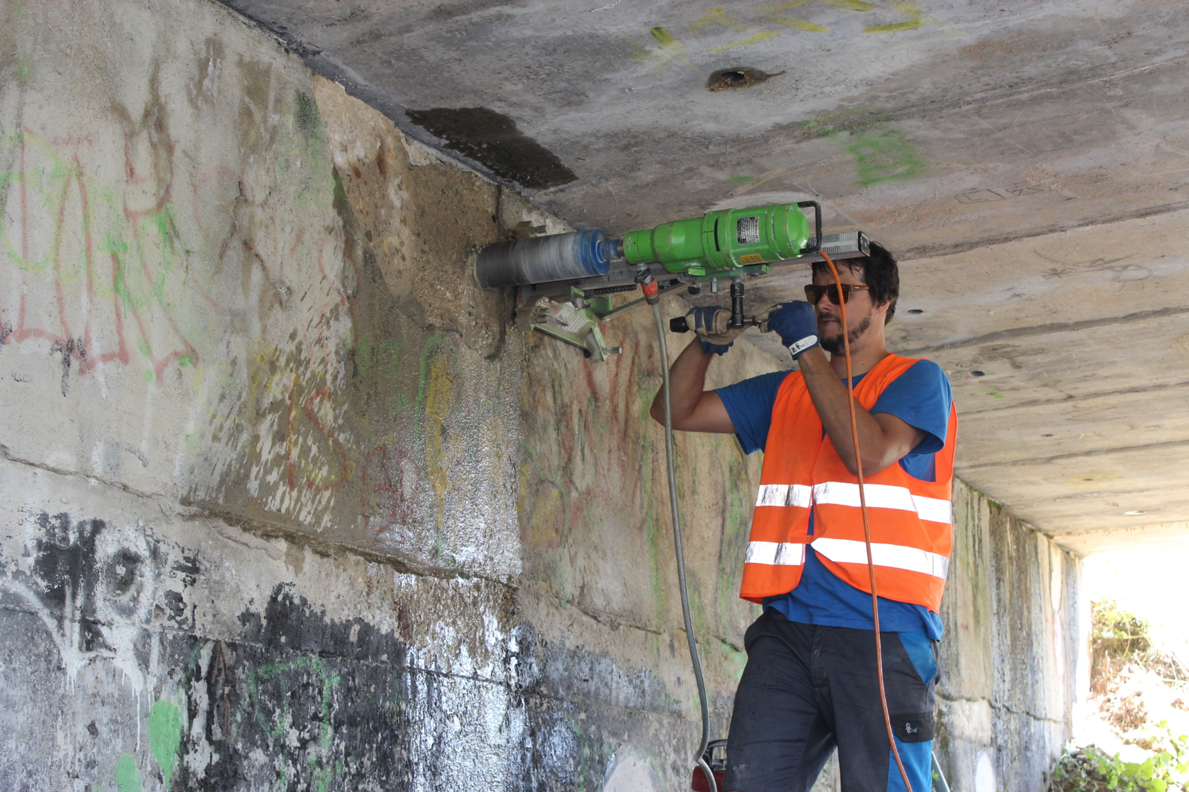 Muž provádí vrt do mostní konstrukce